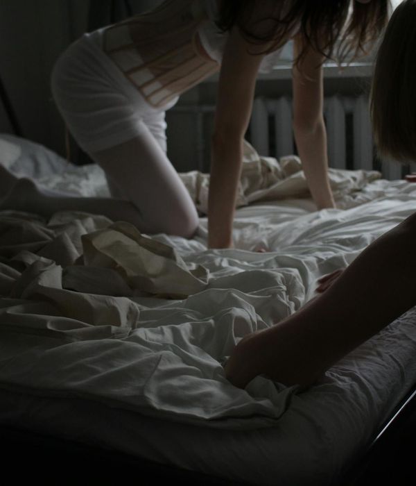 Woman performing a gentle yoga pose in a dark room with fuchsia light.